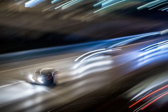 Autos, die nachts auf einer Straße fahren. Man sieht alles nur verschwommen, die Lichter sieht man nur in Form von Lichtmalerei.