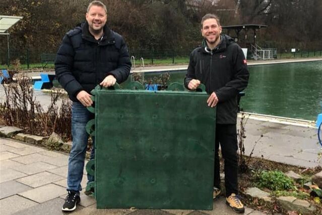 Christopher Lonzynski überreicht Dirk Weise die Bodenplatten für den Umbau des Kinderbeckens.