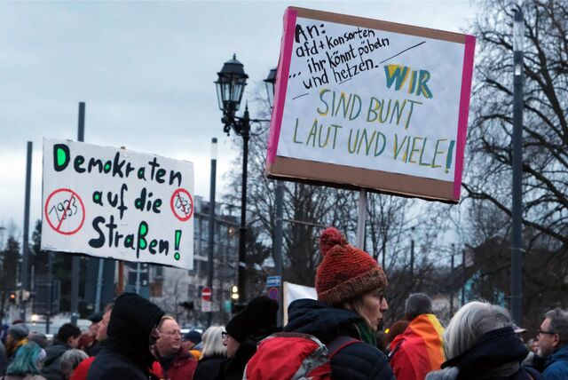 Demonstranten tragen bei einer Kundgebung Plakate für Demokratie und Vielfalt