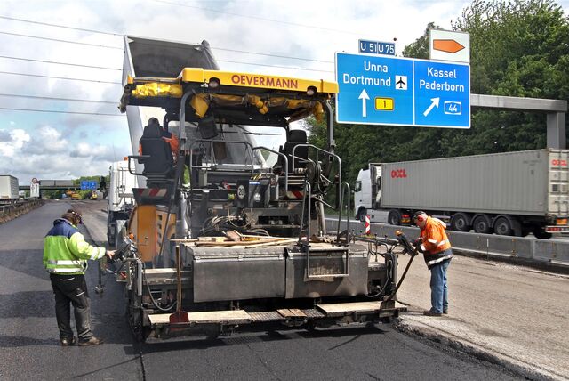 Bauarbeiter erneuern mit einer Maschine den Asphalt auf einem Abschnitt der Autobahn 1 bei Unna