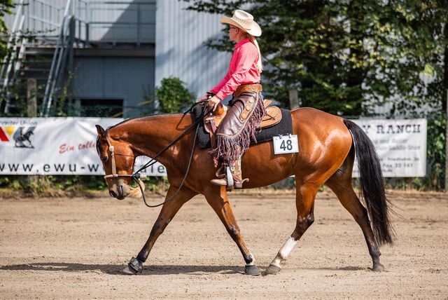 Ann-Katrin Schulz ist Westernreiterin. Auf dem Foto reitet sie ein braunes Pferd im Westernstil.