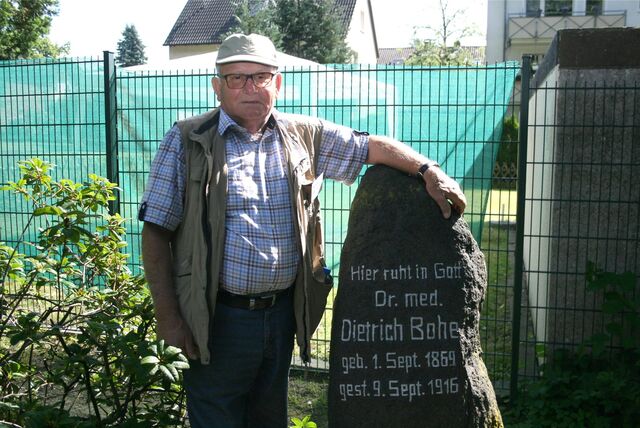 Gerd Koepe ist einer der Gästeführer. Auf dem Bild steht er neben dem Grabstein von Dr. Dietrich Bohe.