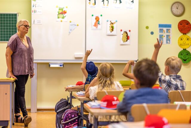 Eine Lehrerin steht in einer Grundschulklasse.