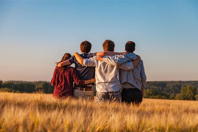 Jugendliche stehen auf einem Feld und umarmen sich.