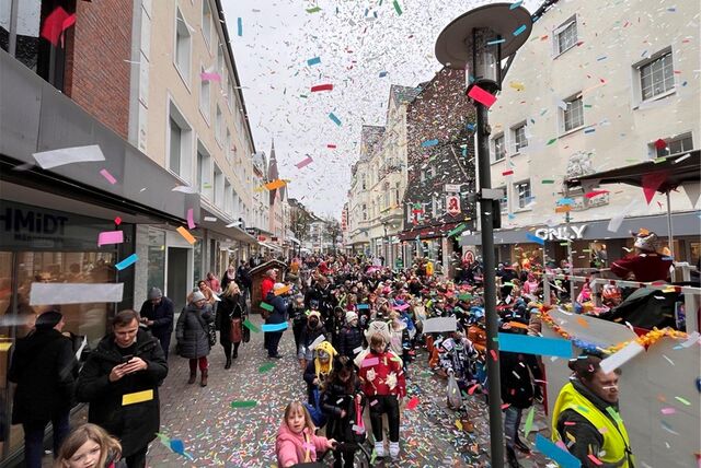 Viele bunt verkleidete Kinder ziehen beim Kinderkarneval durch die Innenstadt von Unna. Konfetti fliegt durch die Luft.