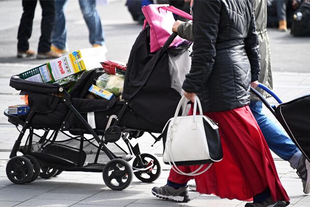 Eine Frau und ein Mann schieben einen Kinderwagen, der mit Einkäufen vollgestopft ist.