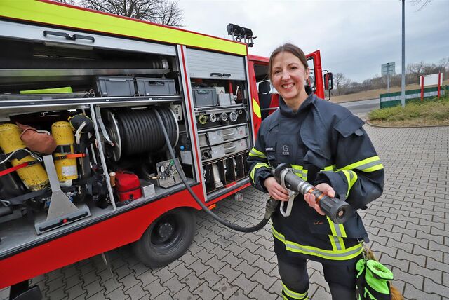Feuerwehrfrau Marta Encarnacao hält einen Lösch-Schlauch, den sie aus einem Feuerwehrwagen vor dem Gerätehaus in Unna-Alte Heide abgerollt hat.