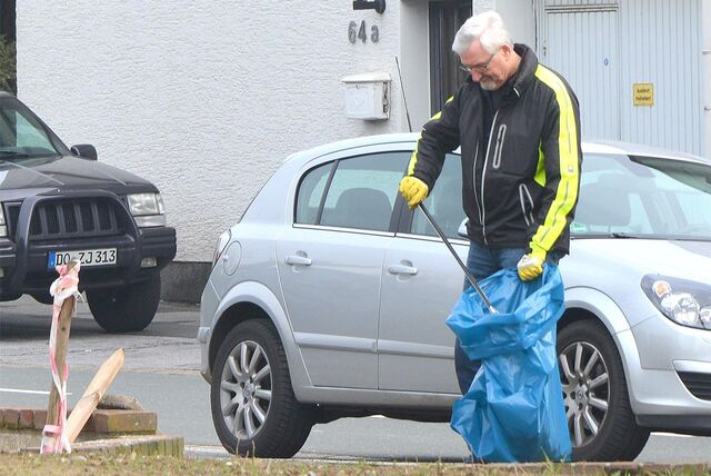 Ein Mann sammelt in Holzwickede während einer Müllsammelaktion im Jahr 2023 Unrat von der Straße auf und befördert sie mithilfe eines Greifers in einen Müllsack.