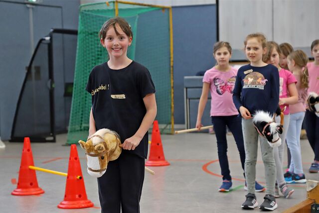 Kinder mit „Hobby-Horses“ in einem Parcours.