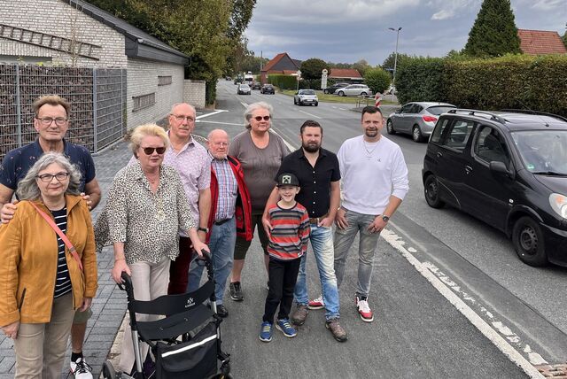 In Unna stehen im Oktober 2023 Bewohner des Ortsteils Alte Heide an der Hammer Straße. Neben ihnen fahren Autos vorbei.