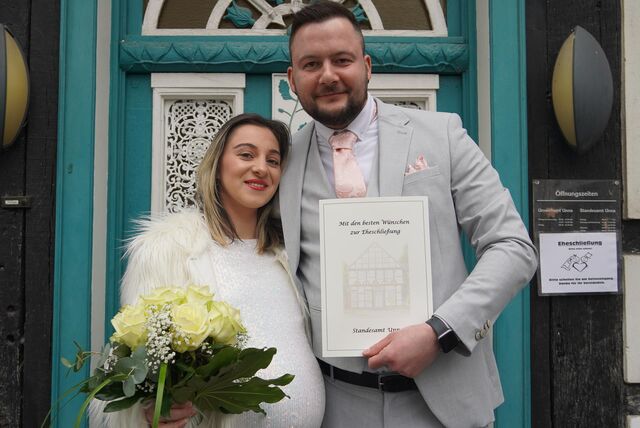 Alexandra und Sebastian Zipfel stehen vor dem Standesamt in Unna mit Brautstrauß und Urkunde.