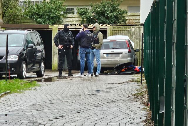Polizisten stehen auf einem Hof.