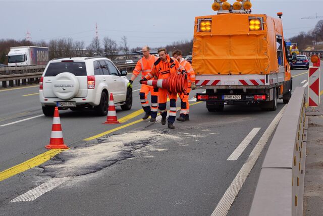 Im Autobahnkreuz Dortmund/Unna wird ein Fahrbahnschaden ausgebessert. Arbeiter in Signalkleidung sammeln die Absperrpylonen wieder ein