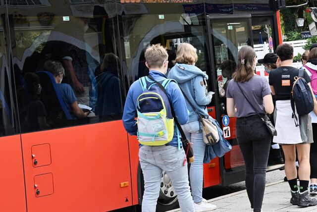 Fahrgäste warten auf den Einstieg in einen Bus.