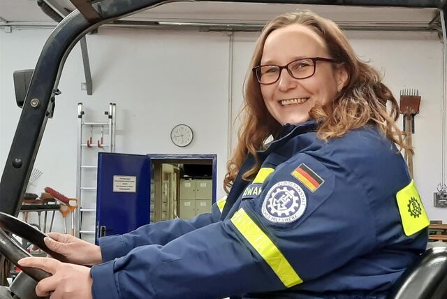 Nadine Nowak sitzt auf einem Hubwagen. Sie trägt die Uniform des THW.