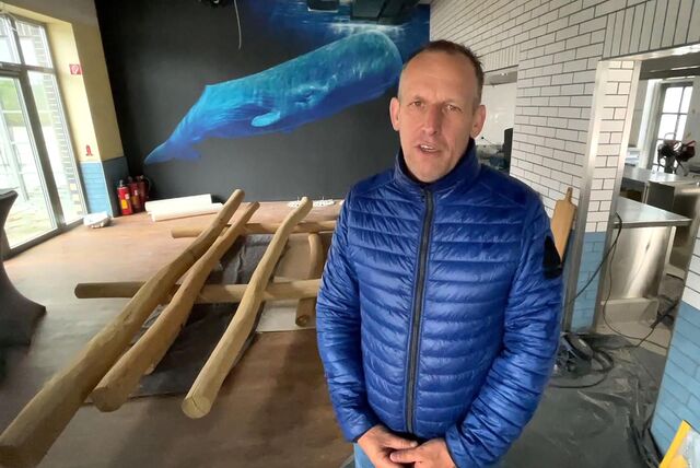 Ein Mann in blauer Jacke steht in seinem Lokal. Im Hintergrund ist die Küche und ein Bild eines Wals zu sehen. (Archivbild)