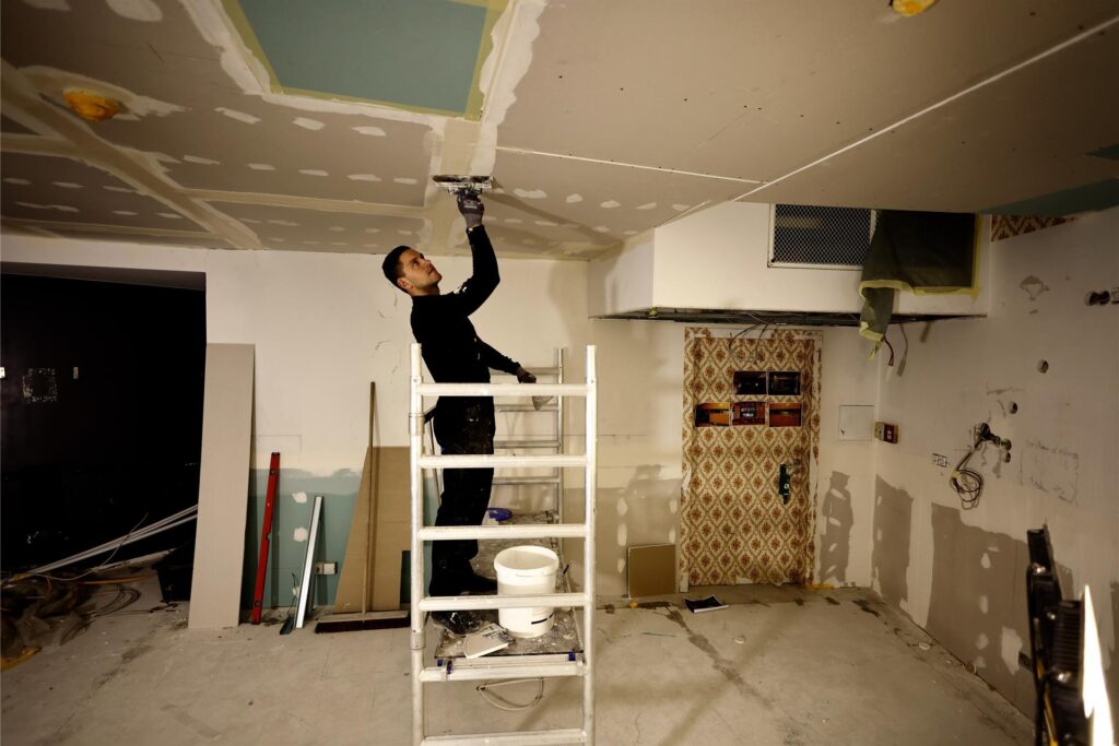 Ein Handwerker verputzt eine Zimmerdecke. Ein Handwerker verputzt eine Zimmerdecke.
