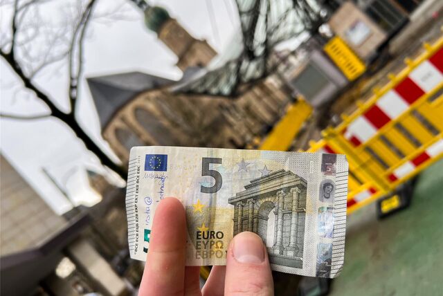 Ein Dortmunder hält einen 5-Euro-Schein vor der Reinoldikirche hoch.