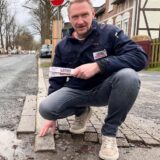 Frank Löbbe, Geschäftsführer des Sanitär- und Heizungsunternehmen Löbbe, kniet an der Hammer Straße vor großen Schlaglöchern. Die Situation an seiner Betriebseinfahrt macht ihm und seinen Mitarbeitern zu schaffen.