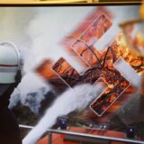 Bildermontage eines Feuerwehrmannes, der in brennendes Hakenkreuz löscht.