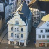 Eine Luftaufnahme, auf der die Gebäude, in denen sich Schnückel und Hussel befinden, aus der Vogelperspektive zu sehen sind.