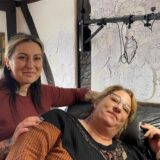 Gewinner Melanie Hofmeister-Nolte liegt auf der Liege in einem Tattoo-Studio und hinter hier steht Katja Baranowski, Inhaberin des Tattoo-Studios „Kattoo“.