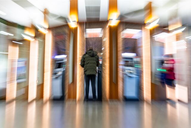 Eine Person steht an einem Bankautomaten.