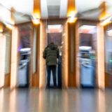 Eine Person steht an einem Bankautomaten.