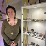 Simone Stache ist Tierkommunikatorin und steht neben einer Glasvitrine voller Schmuck.