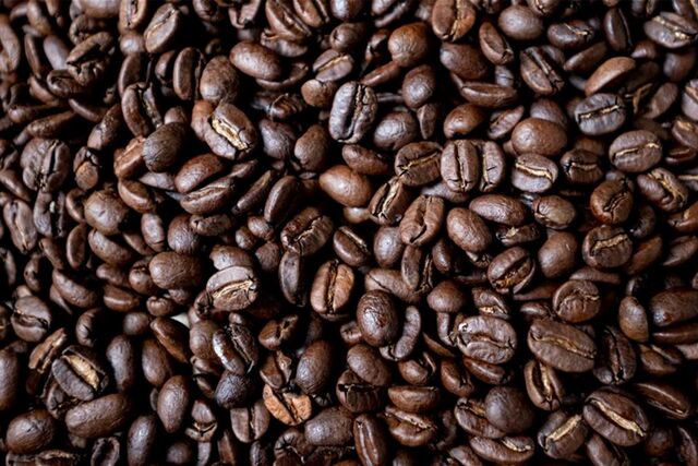 Geröstete Kaffeebohnen liegen auf einem Tisch.