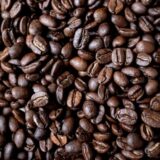 Geröstete Kaffeebohnen liegen auf einem Tisch.