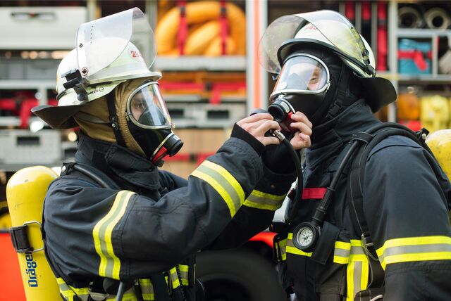 Ein Feuerwehrmann überprüft bei seinem Kameraden das Atemschutzgerät