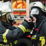 Ein Feuerwehrmann überprüft bei seinem Kameraden das Atemschutzgerät