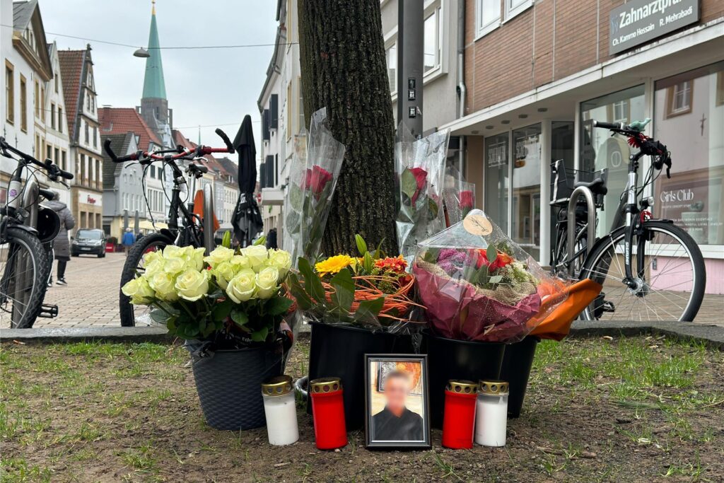 Blumen und Trauerkerzen stehen nahe der Stelle, an dem am Samstagabend in der Bielefelder Innenstadt Besar Nimani (38) durch Schüsse getötet worden war.