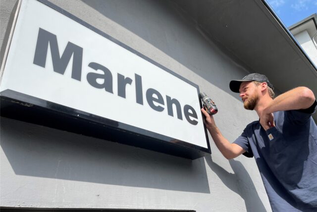 Nico Nahalewicz schraubt das Schild der Marlene Bar ab, um es zu seinem neuen Platz in einer anderen Dortmunder Gastronomie zu bringen.