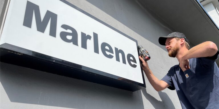 Nico Nahalewicz schraubt das Schild der Marlene Bar ab, um es zu seinem neuen Platz in einer anderen Dortmunder Gastronomie zu bringen.