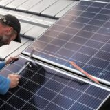 Ein Fachmann montiert eine PV-Anlage auf einem Dach.