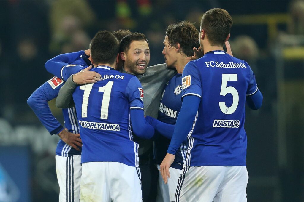 Fußball: Bundesliga, Borussia Dortmund - FC Schalke 04, 13. Spieltag am 25.11.2017 im Signal Iduna Park, Dortmund (Nordrhein-Westfalen). Trainer Domenico Tedesco (M) von Schalke wird nach dem 4:4 gegen Dortmund von seinen Spielern bejubelt. Foto: Ina Fassbender/dpa ++ +++ dpa-Bildfunk + Fußball: Bundesliga, Borussia Dortmund - FC Schalke 04, 13. Spieltag am 25.11.2017 im Signal Iduna Park, Dortmund (Nordrhein-Westfalen). Trainer Domenico Tedesco (M) von Schalke wird nach dem 4:4 gegen Dortmund von seinen Spielern bejubelt. Foto: Ina Fassbender/dpa ++ +++ dpa-Bildfunk +
