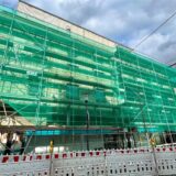 An der Fassade des Kaufhauses Schnückel in Unna steht ein Baugerüst. Davor hängt ein grünes Sicherheitsnetz.