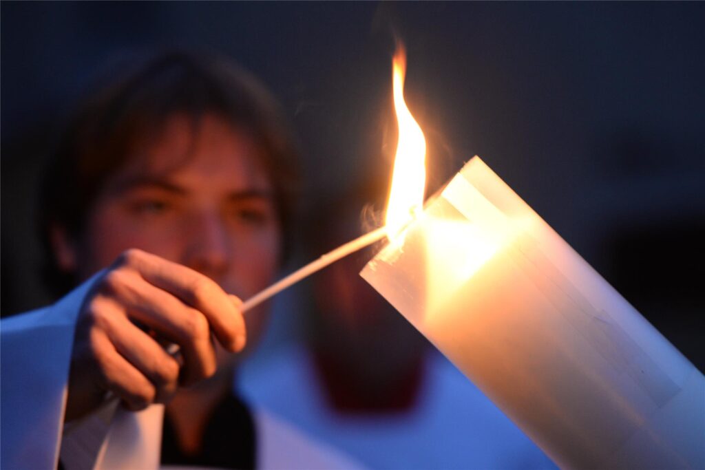 Ein Messdiener zündet in der Osternacht die Osterkerze an.