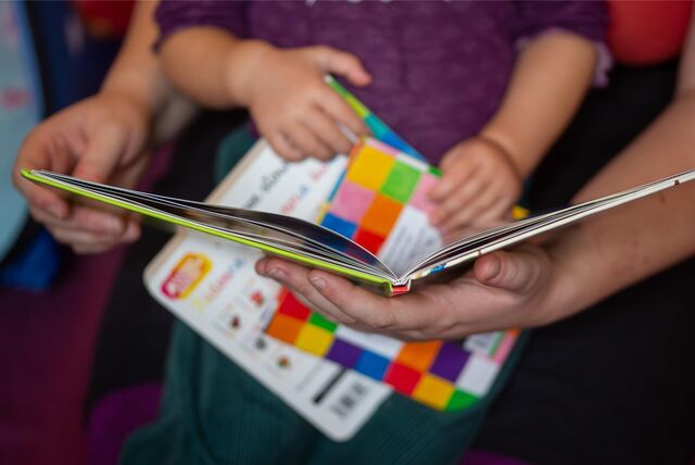 Eine Mutter liest ihrer kleinen Tochter im Kinderzimmer aus einem Buch vor.