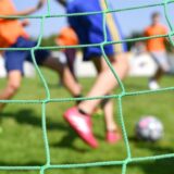 Kinder spielen auf einem Sportplatz Fußball.