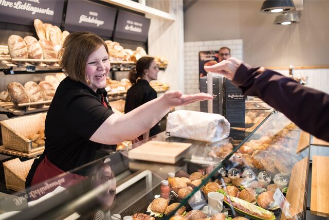 Eine Verkäuferin nimmt in einer Bäckerei in Duisburg (NRW) Bargeld von einem Kunden entgegen.