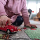 Ein Kind spielt in einem Kindergarten mit einem roten Spielzeugauto
