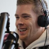 Marvin Schuster lacht, vor einem Mikrofon.