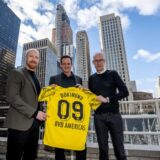 Benedikt Scholz, Marc Lingenhoff und Carsten Cramer halten ein BVB-Trikot hoch.
