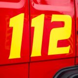 Die Notrufnummer 112 steht gemeinsam mit einem Telefonhörer-Symbol auf der Tür eines Feuerwehrfahrzeugs.