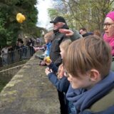 Kinder werfen beim ersten Werner Entenrennen in 2024 Enten in den Horne-Fluss.