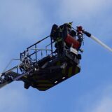 Von einer Drehleiter aus gehen Feuerwehrleute gegen die Flammen vor.