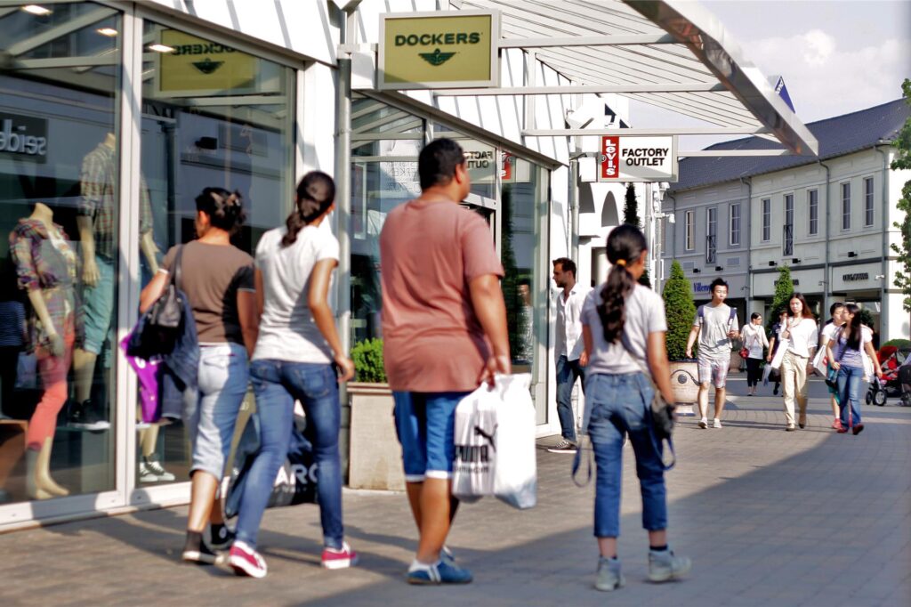 Besucher gehen im Designer Outlet Roermond an Geschäften vorbei. Besucher gehen im Designer Outlet Roermond an Geschäften vorbei.